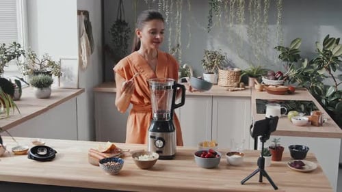 Woman Making Smoothie with Blender in Kitchen