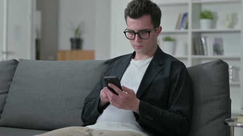 Young Male Designer Using Smartphone at Home