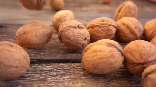 Fresh Walnuts Dropping on Rustic Wooden Table