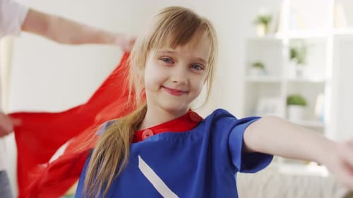 Smiling Girl Plays Superhero with Red Cape