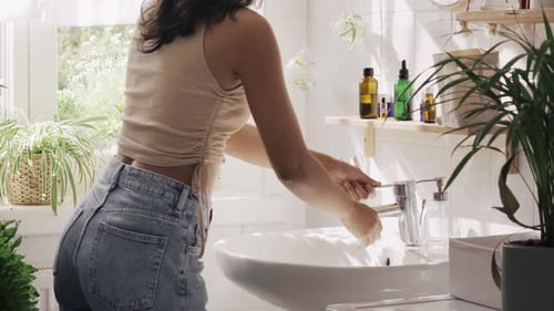 Woman Washing Hands in Bathroom Sink