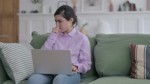 Indische Frau mit Laptop hustet auf Sofa