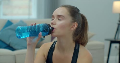 Woman Drinks Water after Exercise at Home
