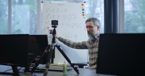 Man Explains Math Lessons to Camera at Desk