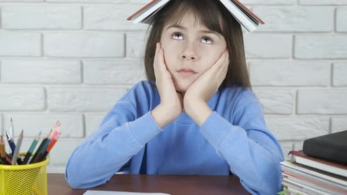 Tired child with a book on head.