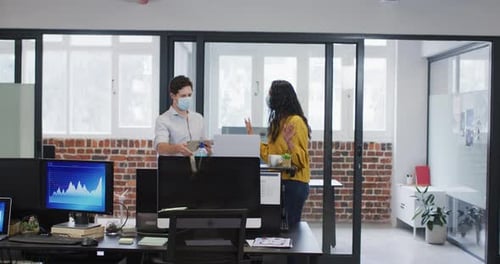 Man and woman wearing face mask working together in office