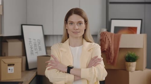 Woman Smiles Confidently in Kitchen Packed with Boxes