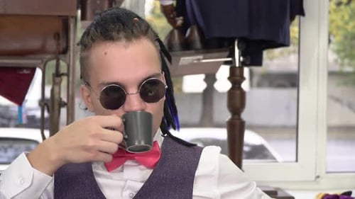 Young Successful Fashionable Businessman Drinks Coffee in a Cafe