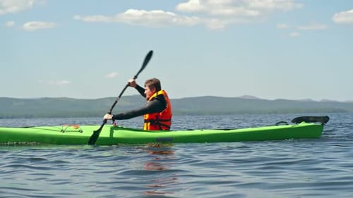 Man Paddling Kayak on a Sunny Lake