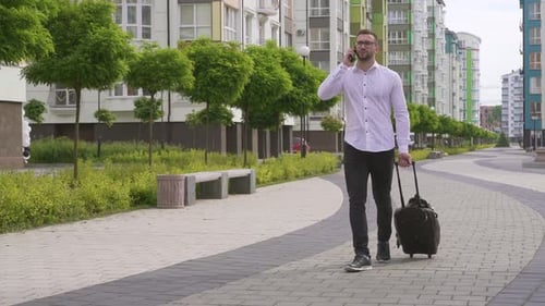 Man Walking with Suitcase Talking on Phone
