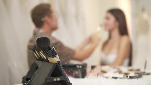 4K Asian LGBTQ guy make-up artist applying makeup to female bride customer at wedding studio.