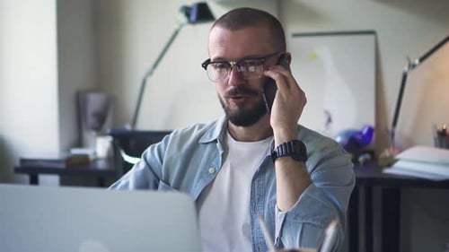 Handsome Man Manager Talking on the Phone in Office with Laptop Computer