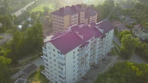 Aerial view of multistory apartment building in green residential area.