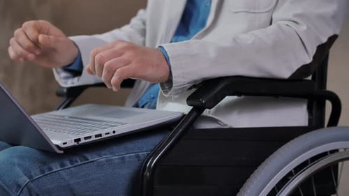 Man in Wheelchair Using Laptop Computer Indoors