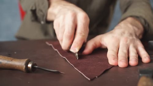 Guy Working with Leather Using Crafting Tool at Workshop.