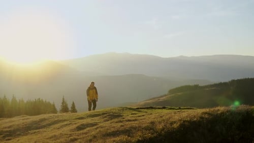 Lone Hiker Walking Across Hilltop at Sunrise