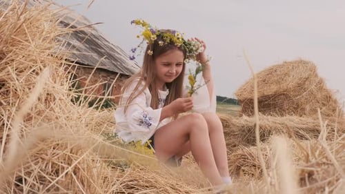 Girl with Flower Wreath Sitting in Golden Hay