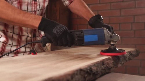 Ein Arbeiter schleift ein Stück Holz