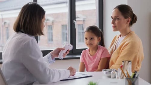 Mother with Sick Daughter and Doctor at Clinic