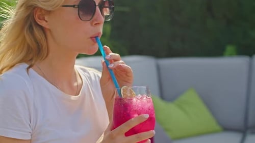 a Beautiful Young Woman in a White Tshirt is Enjoying a Wonderful Cocktail in Hot Summer in a Cool