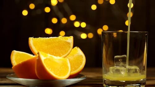 Pouring Fresh Orange Juice into Glass with Ice
