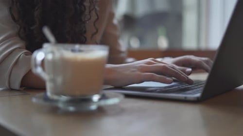 Woman Working And Typing On Laptop Computer With A Cup Of Hot Coffee