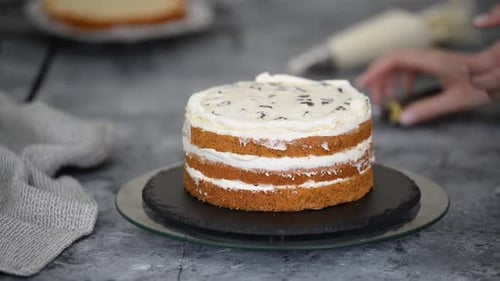 Confectioner Rotates the Cake on a Stand and Decorates with Cream From the Pastry Bag