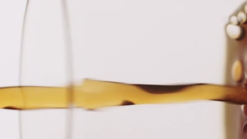 Vertical video of coffee/dark liquid getting poured into glass. Detail shot of coffee in slow-motion