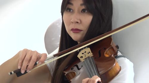 Woman of Asian Appearance Playing a Violin. Close Up