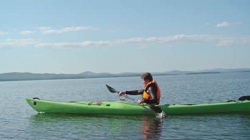 Kayaker Paddling Bright Green Kayak on Lake