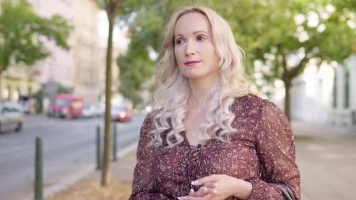 A Middleaged Caucasian Woman Thinks About Something in an Urban Area a City Street