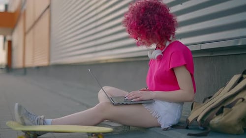 Young Adult Works on Laptop Outdoors in City