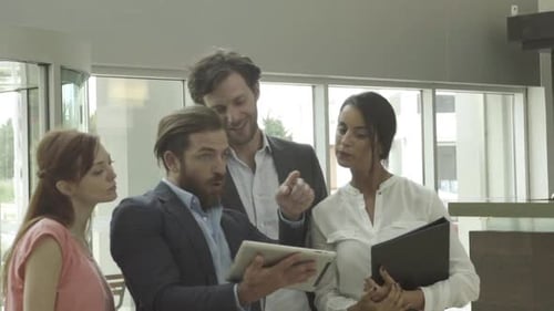 Businessman talking with clients and using digital tablet in lobby