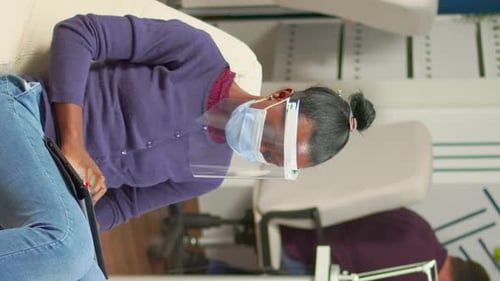 Woman with Face Shield Looks at Tablet Indoors