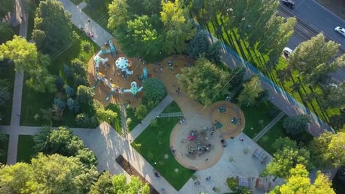 Kinderspielplatz in Parkanlage in der Stadt am sonnigen Abend, Luftbild