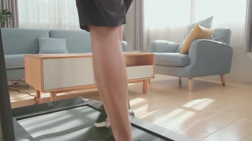 Back View Of Asian Man Training On Walking Treadmill At Home