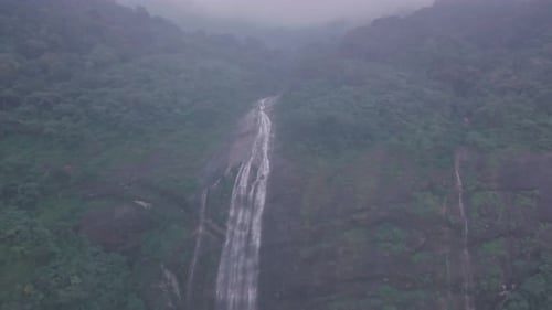 Waterfall in misty mountain scenery. Aerial drone view of beautiful Indian scenery