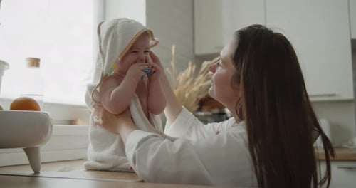 Mother Smiles at Adorable Infant Wrapped in Towel
