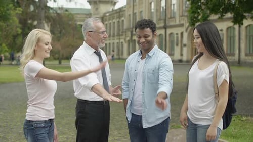Happy teacher and multiracial students putting hands on pile, team building