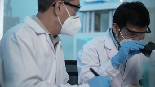 Scientists Using Microscope in Modern Laboratory Setting