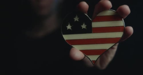 Hand Holding Patriotic American Flag Heart Pin