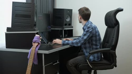 Sound engineer music producer mixing and mastering pop rock song hits infront of monitors and laptop
