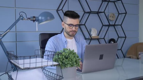 Professional Creative Man Sitting at His Desk in Home Office Studio Working on a Laptop
