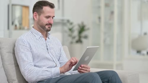 Man Using Tablet While Relaxing on Sofa