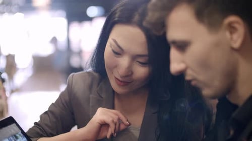 Empresária asiática e colega discutindo trabalho no bar