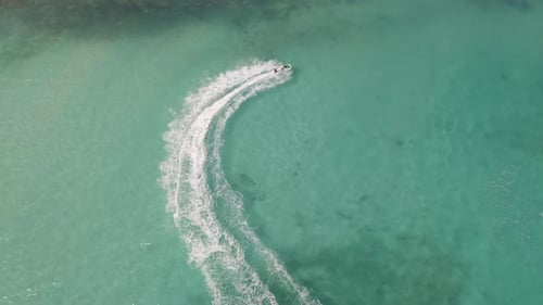 Aerial top view of jet ski or boat drawing a shape on sea ocean turquoise water. Adventure