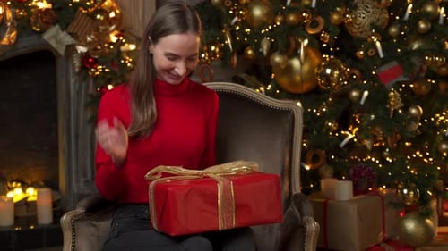 Woman Unwraps Christmas Gift in Cozy Setting