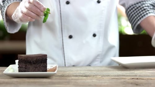 Chef Garnishing Chocolate Cake with Mint and Sugar