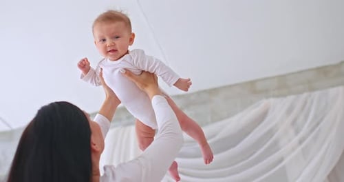 Loving Mother Holds Baby Up in Indoor Setting
