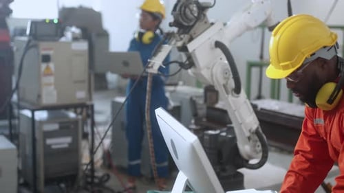 caucasian engineer technician control manage robot arm welding automation with computer monito